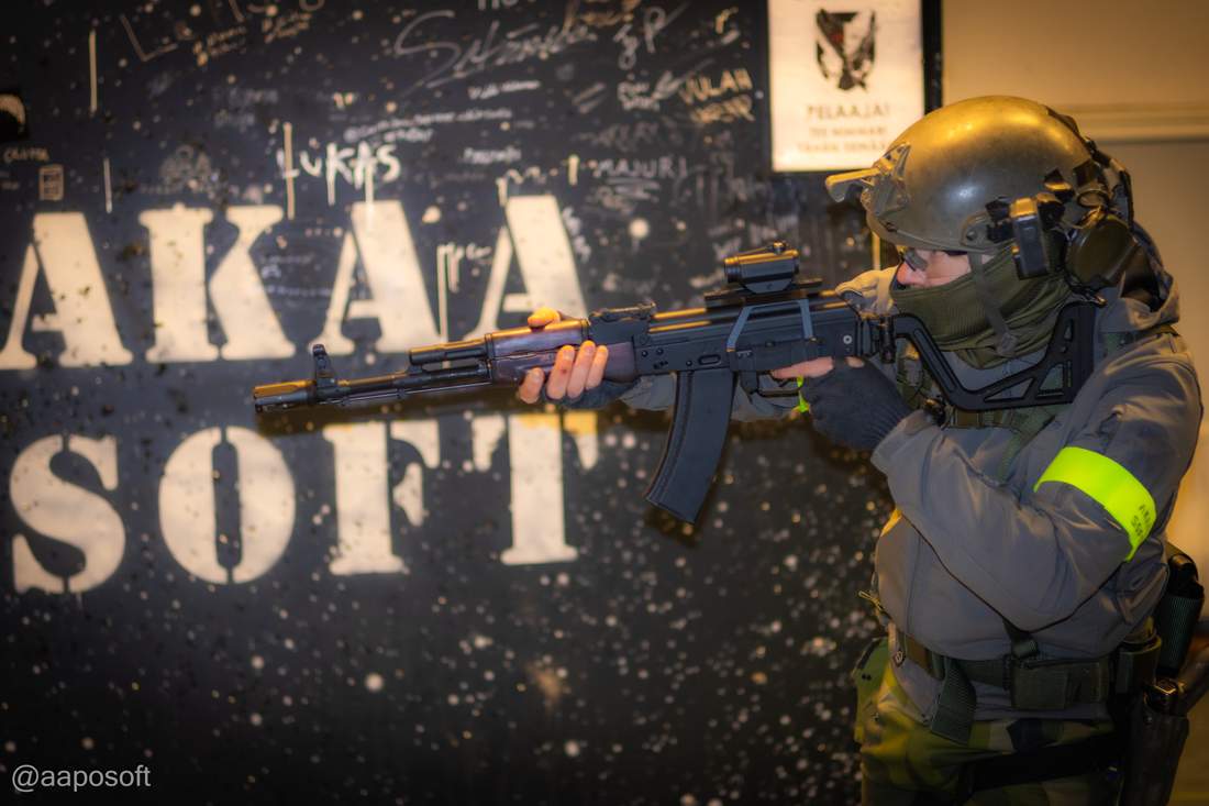 Kylmis-pelipaikka — airsoft-pelaaja replikan kanssa Kylmäkosken koulun graffiti-seinämaalauksen AKAASOFT edessä, sisätila